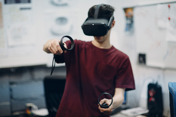 Young man in virtual reality goggles, vr glasses headset with joystick