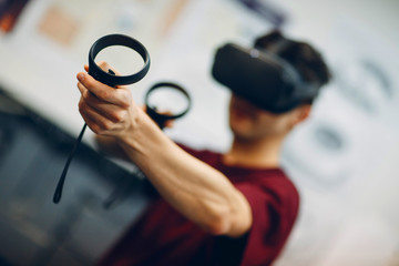 Young man in virtual reality goggles, vr glasses headset with joystick © primipil
