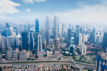 Crédence de cuisine en verre imprimé Kuala Lumpur KUALA LUMPUR - Malaysia. November 12, 2019: Aerial view of Petronas Twin Towers and near highway in Kuala Lumpur CBD area shot at midday over blue sky