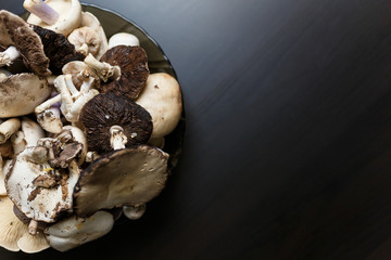 Raw champignons standing on black wooden table. Healthy organic vegetarian food. Diet, nutrition, eating habits concept. Copy space