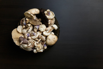 Raw champignons standing on black wooden table. Healthy organic vegetarian food. Diet, nutrition, eating habits concept. Copy space