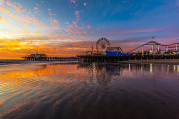 Santa Monica Pier with firey sky sunset. reflection of sky in water.