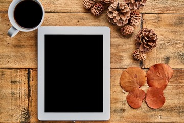 Tablet on wooden table with fall decoration.