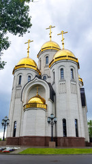 Church building on a sunny summer day. White orthodox temple with golden domes among trees.