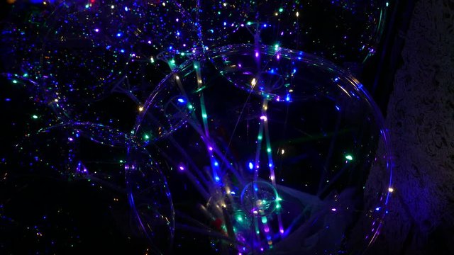 Transparent balloon with colorful LED lights against dark background