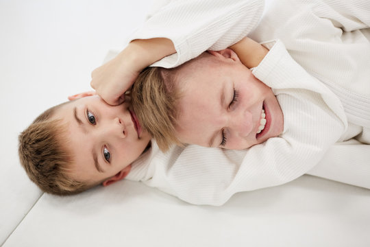 Two boys lying on the floor and fighting with each other during training in karate