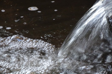 fließender Bach  Detail-Aufnahme kristallklares Wasser mit Wassertropfen Spritzer und schwarzem Hintergrund, Detail-Aufnahme romantische frische natürliche Ansicht mit Platz für Texte	