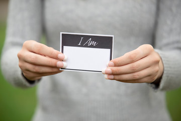 Hands holding a card that says I Am
