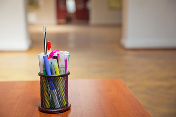 Box for pens and pencils . Colored pencils in a pencil case on the wooden table . Color pencils in black case . Close-Up color pencils and markers in metal glass on wooden background .