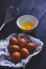 EGGS ON OVEN PAPER NEXT TO BATTERY AND BOWL WITH EGG YOLK