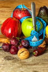 Concept diet.  Healthy food. Fruits on a wooden board wrapped with measuring tape on a wooden table. Weigh loss concept.