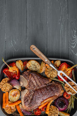 tender and juicy steak on the bone grilled next to baked and grilled vegetables, the concept of tasty and healthy nutrition