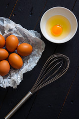 EGGS ON OVEN PAPER NEXT TO BATTERY AND BOWL WITH EGG YOLK