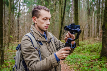 male blogger films himself in the woods on a mobile phone camera and gimbal. concept of blogging, Internet, information
