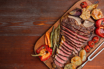 marbled beef steak on the bone cooked to a state of medium rare grill. next to the steak, grilled vegetables serving as a side dish. lovely gala dinner for two