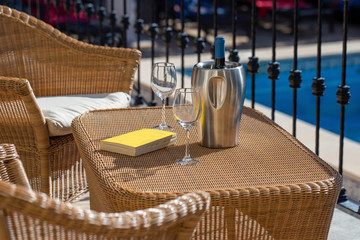 Corner for relaxation in front of the pool with a book and wine. In a hotel.