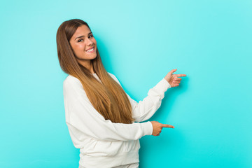 Young slim woman excited pointing with forefingers away.