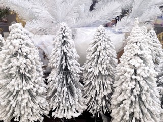 Artificial Christmas tree with snow, selective focus. Small Decorative artificial christmas trees with white snow on the needles in Christmas market 