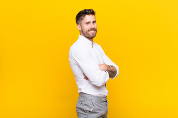 young handosme man smiling to camera with crossed arms and a happy, confident, satisfied...
