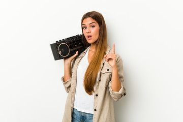 Young caucasian woman holding a guetto blaster having an idea, inspiration concept.