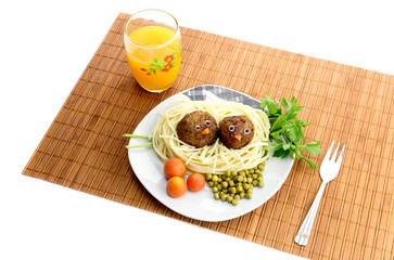 Children's meal - pasta with meatballs and fruit juice on the table close-up