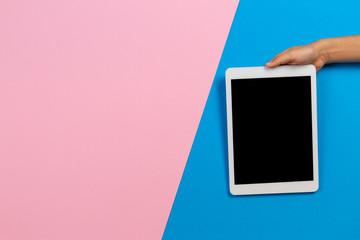 Kid hands with digital tablet computer on pastel pink and light blue background