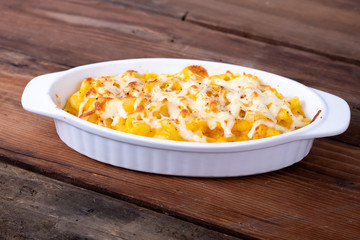 Butternut squash mac and cheese dish closeup on a rustic table and grated cheese on top