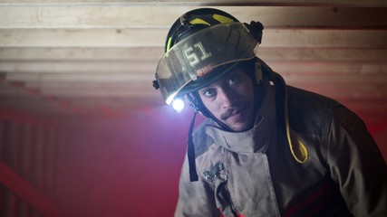 Fire Figher in smokey crawl space looking directly into camera - close up on face