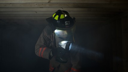 Fire fighter searching for survivors in crawl space shining light