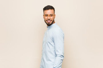 Young south-asian business man looks aside smiling, cheerful and pleasant.