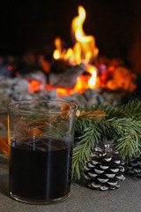 in the furnace the fire burns, a candlestick and a fir-tree, the new year's atmosphere, the burning hearth in the house, selective focus,wine is poured in a glass