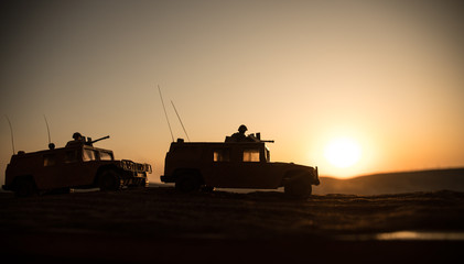 Military patrol car on sunset background. Army war concept. Silhouette of armored vehicle with...