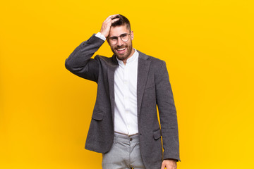 young handosme man laughing and slapping forehead like saying d‚Äôoh! I forgot or that was a...