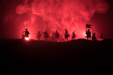 Fototapeta premium Medieval battle scene with cavalry and infantry. Silhouettes of figures as separate objects, fight between warriors on dark toned foggy background. Night scene.
