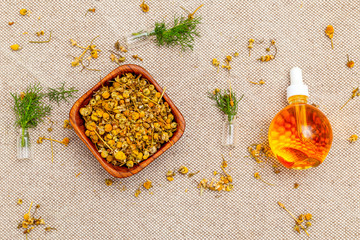 Dry chamomile herbs and oil on linen background.  Healthy lifestyle