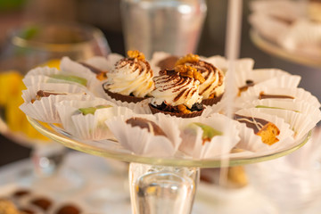 Plate with sweet cakes on pink table against brick wall background