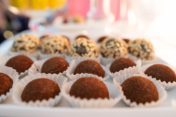 Plate with sweet cakes on pink table against brick wall background