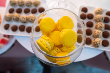 Plate with sweet cakes on pink table against brick wall background