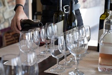 a waiter pouring red wine in a glass placed on a table