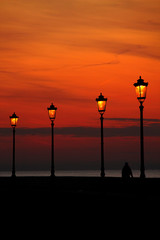lights burning in the evening on the city promenade against the sunset sky