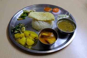  Dal bhat dish served on a metal plate - traditional Nepalese dish with rice, lentil soup and vegetables