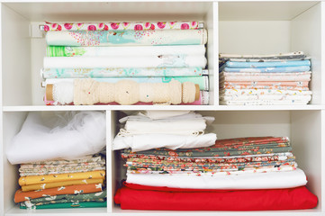 Stack of pieces fabric many pattern on shelf, material recycle for clothing fashion design. Sewing shelf with material.