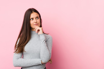 Young cute woman looking sideways with doubtful and skeptical expression.