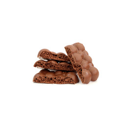 Some pieces of porous chocolate laying on top of each other and one is near on isolated white background.