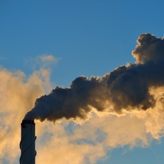 Factory pipe close-up with a lot of smoke against blue sky