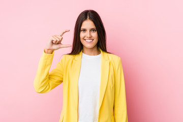 Young business woman holding something little with forefingers, smiling and confident.