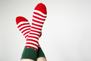 Female feet in Christmas socks on white background. Concept of New Year celebration, elf costume