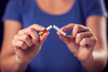 Woman holding broken cigarette in hands. Stop smoking concept