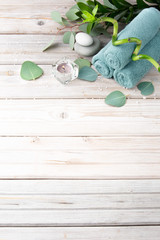 Spa concept. Turquoise towels in a roll, eucalyptus, candle, sea stones, bamboo and tropical leaves on a light wooden background. Top view with copy space.