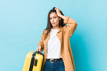 Young caucasian woman holding a suitcase being shocked, she has remembered important meeting.
